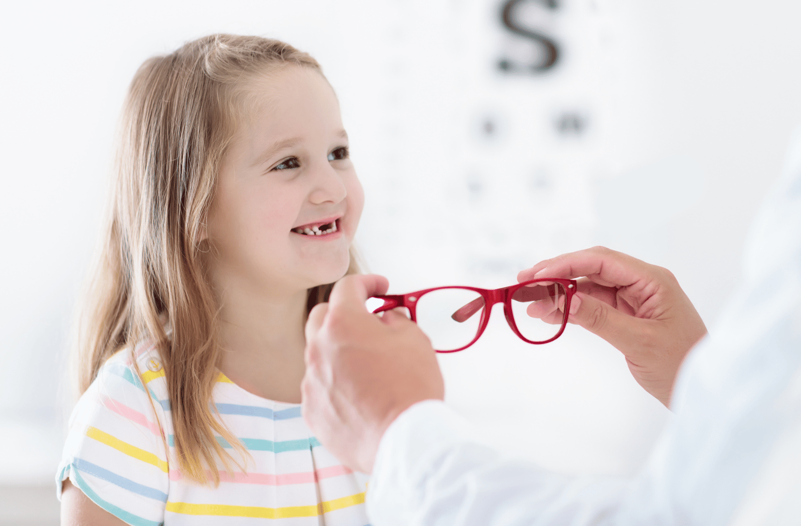 A young girl gets her new glasses fitted for her face at the optometrist's office