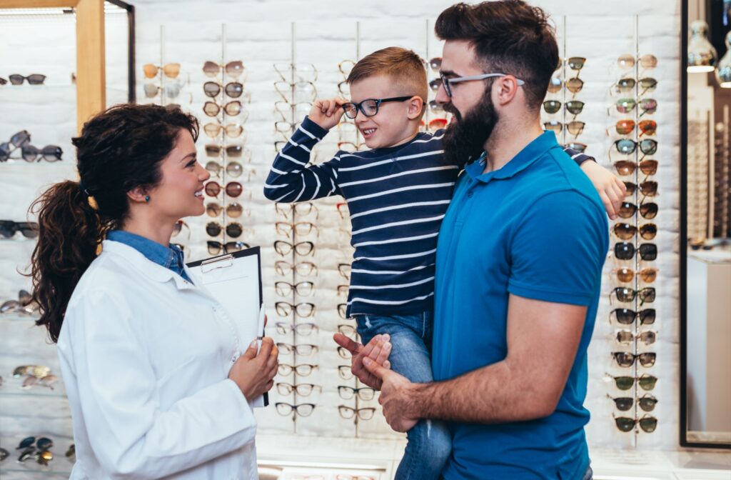 An optometrist helps a parent and child pick out eyeglasses after their appointment